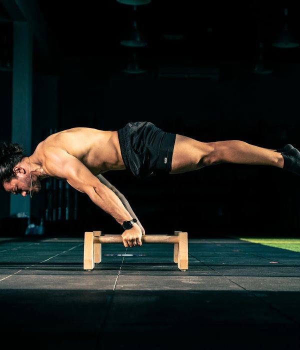 Man performing a controlled core strength exercise in a minimalist dark room.